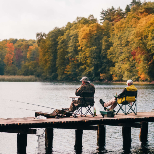 Men fishing from dock with autumn foliage